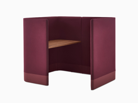 Three-quarter angle of Pullman Desk Pod upholstered in burgundy fabric and walnut top, with screen to the right.