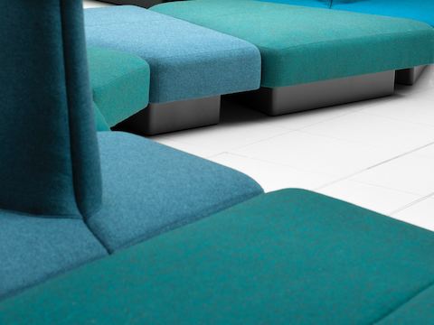 Nahansicht grüner und blauer modularer NaughtOne Rhyme Sitzmöbel-elemente mit schwarzen Untergestellen.