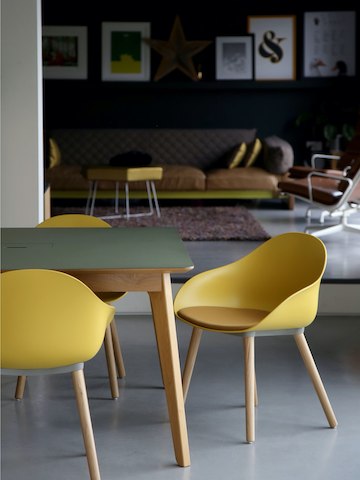 Três cadeiras para visitantes Ruby amarelas com bases em cavilha carvalho com uma mesa.