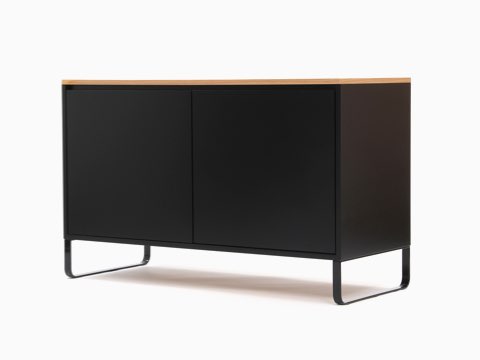 Ein NaughtOne Sideboard ganz in Schwarz mit furnierter Platte in Eiche, im schrägen Winkel betrachtet.