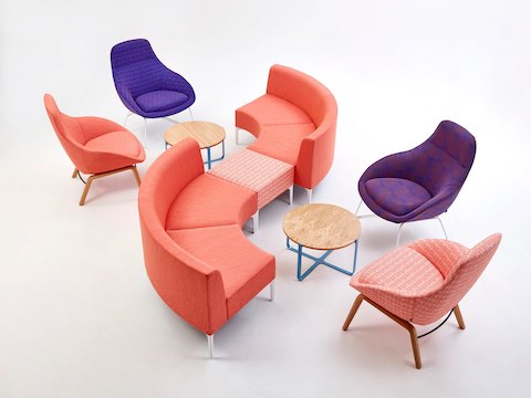 Una banca Symbol para uno en estampado naranja entre dos piezas de sillería modular Symbol a 90 grados color naranja, junto a cuatro sillas lounge Always.