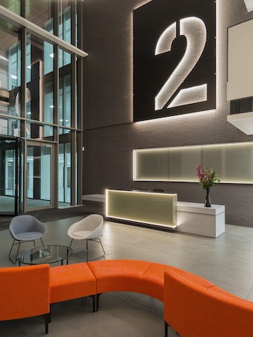 Sedute modulari Symbol arancioni disposte in modo da creare una struttura serpeggiante in una lobby aperta.