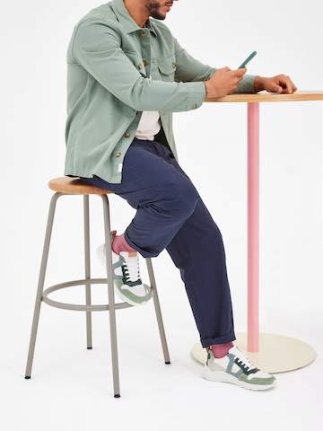 A man sitting on a Penny stool next to a bar height Tier table.