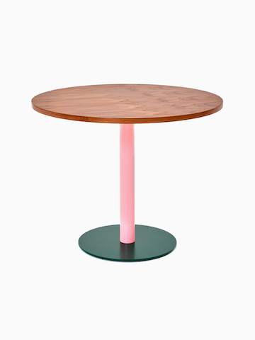 Vista frontal de una mesa redonda Tier con cubierta de chapa de madera de nogal, pilar rosa claro y base verde musgo.