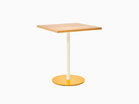 Vista frontale angolare di un tavolo Tier quadrato con piano impiallacciato in rovere, stelo ostrica e base giallo ginestra.
