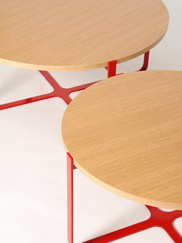 Vista de perto de duas mesas de centro Trace redondas, vermelhas e com tampos em madeira.