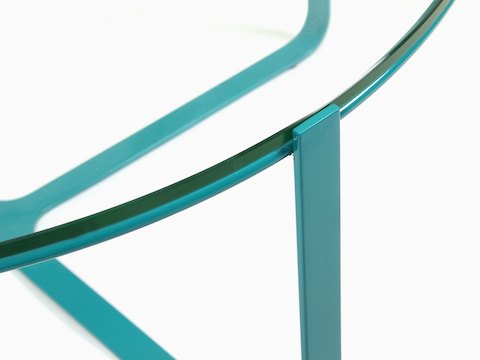 Una vista en primer plano de una mesa de café Trace redonda y azul, con superficie de vidrio.
