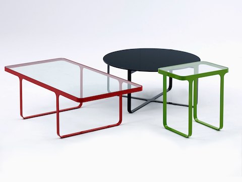 Família de mesas Trace da naughtone, pequenas, com uma mesa de centro Trace vermelha, uma mesa de apoio Trace verde e uma mesa de centro Trace redonda, toda preta.