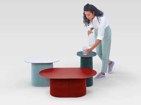Woman placing a glass on a Tun Side Table, among a range of Tun tables.