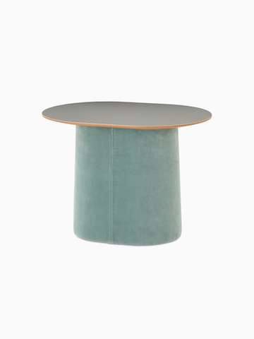 Vista frontale angolare di un tavolo d’appoggio basso Tun con base imbottita azzurra e piano Forbo grigio chiaro.