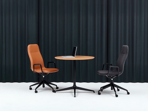 两张搭配5星底座的Viv高靠背扶手椅和搭配黑色4星底座和圆形橡木胶合板桌面的会议桌。