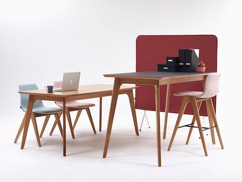 A pink NaughtOne Viv Wood Stool is stationed at a gray Dalby Bar Height Table. Two Viv Wood Chairs are also stationed at another Dalby Table.