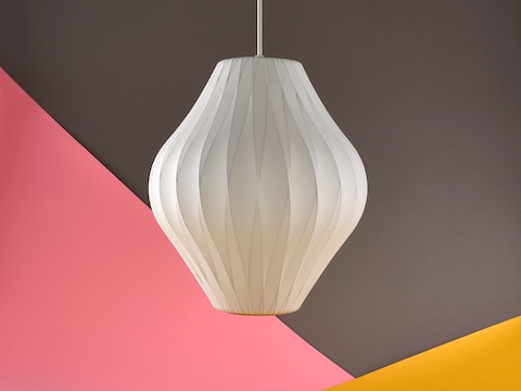 A Nelson Pear Bubble Pendant lamp hanging in front of a brown, yellow, and salmon background. A Nelson Pear Bubble Pendant lamp hanging in front of a brown, yellow, and salmon background.