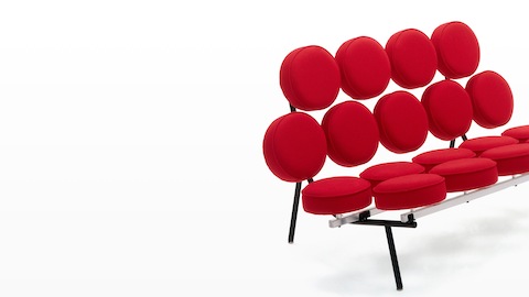 Um sofá Nelson Marshmallow estofado em tecido vermelho, visto de um ângulo de 45 graus. Um sofá Nelson Marshmallow estofado em tecido vermelho, visto de um ângulo de 45 graus.