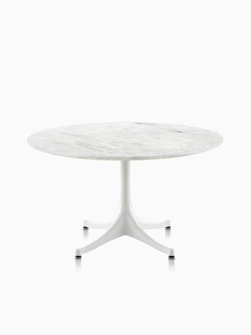 Una mesa redonda Nelson Pedestal al aire libre con una tapa de piedra blanca.