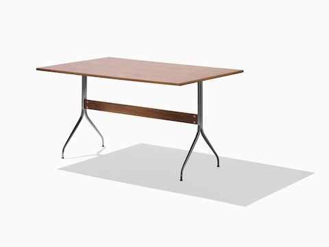 A rectangular Nelson Swag Leg Table in a medium wood finish, showing a single walnut stretcher between tubular steel legs. A rectangular Nelson Swag Leg Table in a medium wood finish, showing a single walnut stretcher between tubular steel legs.
