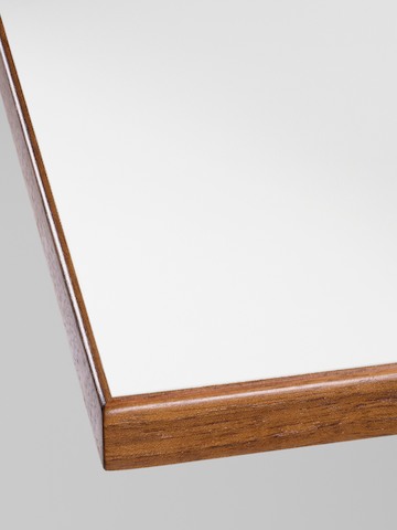 Close-up of the corner detail on a Nelson Swag Leg Table with a white laminate top and walnut veneer edge band. Close-up of the corner detail on a Nelson Swag Leg Table with a white laminate top and walnut veneer edge band.