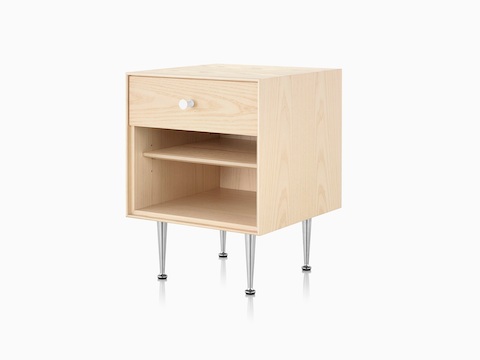 An angled view of a Nelson Thin Edge bedside table with a light finish, white knob, and slim aluminum legs.