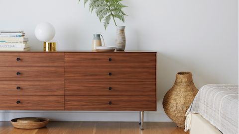 A Nelson Thin Edge double dresser with eight drawers, black knobs, and a medium finish in a residential setting.
