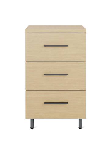 A Nemschoff Bedside Cabinet in an oak on ash finish with three drawers, graphite bar pulls, and metal raised legs.