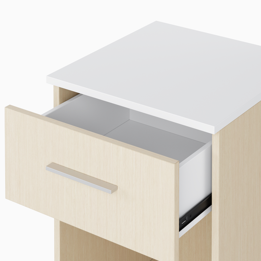 A close-up view of an open drawer with white laminate interior on a Nemschoff Bedside Cabinet.