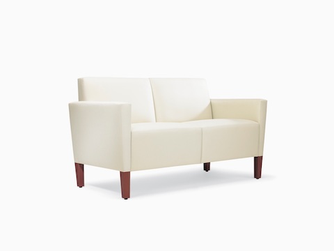A three-quarter view of a Brava Classic Lounge Settee with white textile and upholstered arm caps.