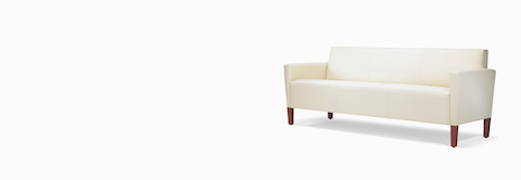 A three-quarter view of a Brava Classic Lounge Sofa with white textile and upholstered arm caps. A three-quarter view of a Brava Classic Lounge Sofa with white textile and upholstered arm caps.