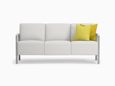Front view of white Brava Modern Lounge Seating three-seat sofa with solid surface arm caps and yellow pillows.