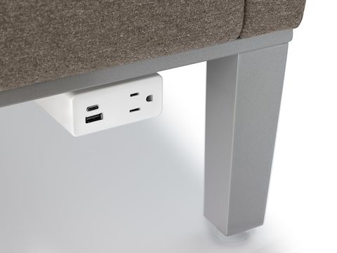 Zoomed-in shot of a white Herman Miller Mini Logic power outlet mounted to the metal base of Brava Platform Lounge Chair.