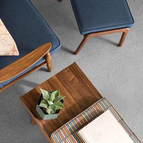 Overhead view of a Nemschoff Aspen Lounge Chair and Ottoman in a walnut frame, arms, and legs, and blue upholstery with a Nemschoff Tamarack Table and Bench in a walnut finish and a multi-patterned cushion.