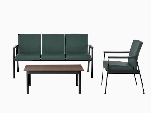 An Easton three-seat Multiple Seating and Easton Side Chair, both in green upholstery and black frames, sit across from an Easton Coffee Table with a medium-matte walnut laminate top and black frame. An Easton three-seat Multiple Seating and Easton Side Chair, both in green upholstery and black frames, sit across from an Easton Coffee Table with a medium-matte walnut laminate top and black frame.