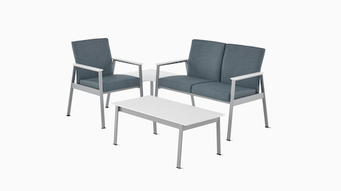 An Easton Side Chair and Easton two-seat Multiple Seating, both in blue upholstery with silver frames, connect to an Easton corner table in glacier white Corian with a silver frame and sit across from an Easton Coffee Table in glacier white Corian with a sliver frame.