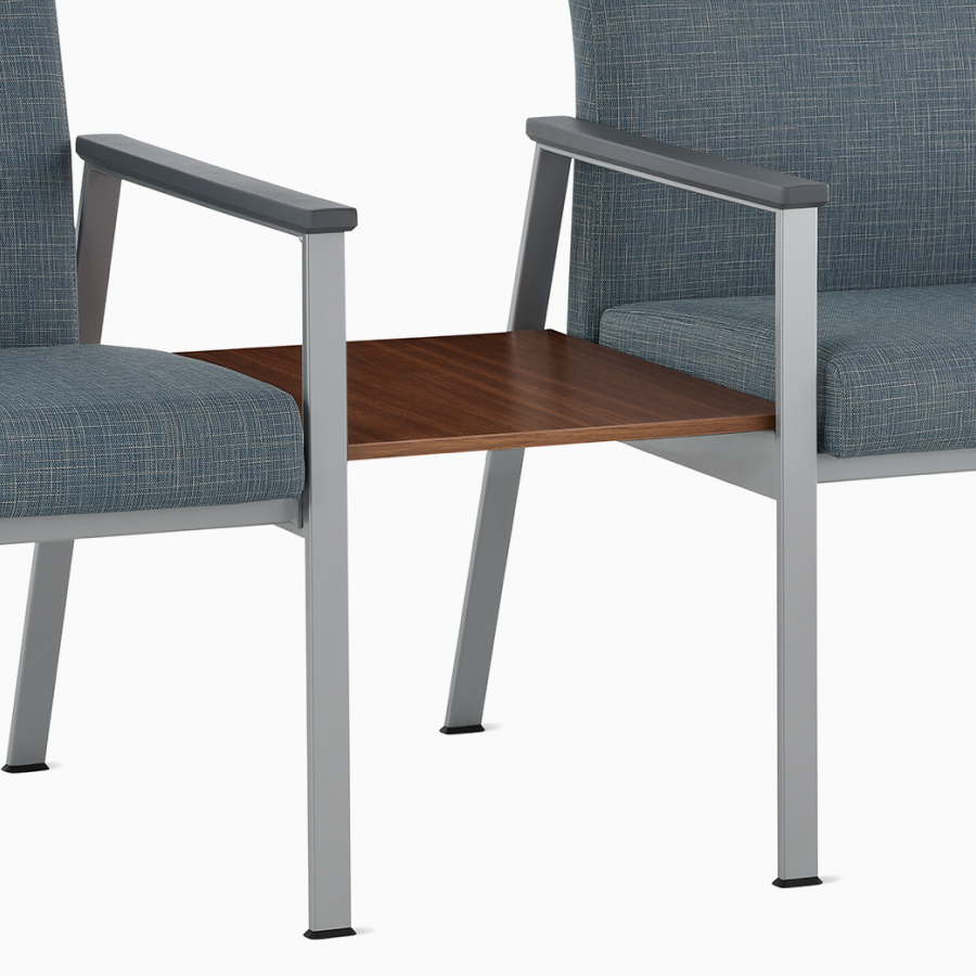 An Easton Side Chair and Plus Chair in blue upholstery connected by a table with a medium matte walnut laminate top.