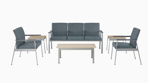 An Easton Plus Chair, Easton three-seat Multiple Seating, and Easton Side Chair, all in blue upholstery, sit next to Easton Side Tables and across from an Easton Coffee Table with clear on ash laminate tops and metallic silver frames.