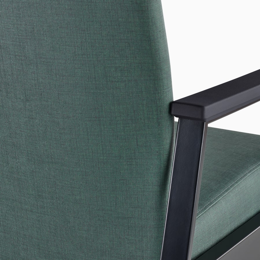 Detail of the back of an Easton chair in green upholstery, black frame, and black arm caps.