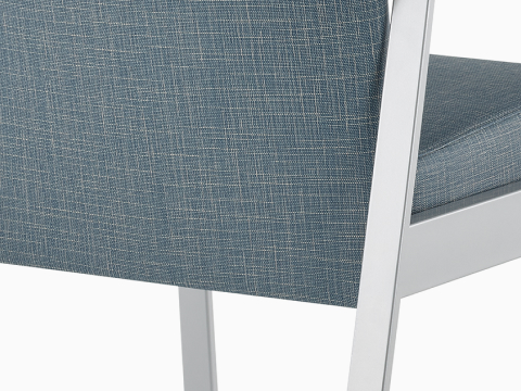 Detail of an Easton chair with blue upholstery and metallic silver four-leg base.