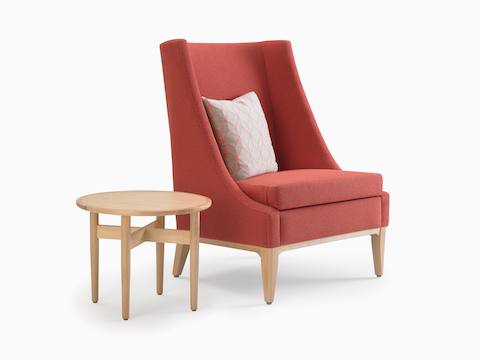 Angled view of Nemschoff Iris Lounge Chair in red upholstery and light wood base and legs and a Hemlock Side Table in light wood.
