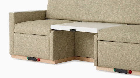 Angled view of a Nemschoff Merge 2 Flop Sofa in a beige upholstery with a white center table and a natural maple base.