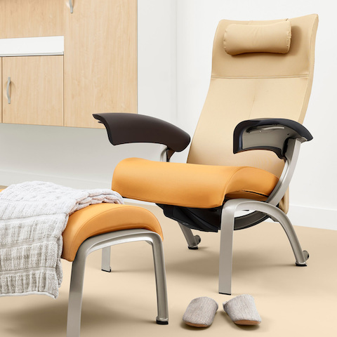 A patient room with a Nemschoff Nala Patient Chair and Ottoman upholstered in multiple fabrics with dark brown arms with Compass System casework on the wall.