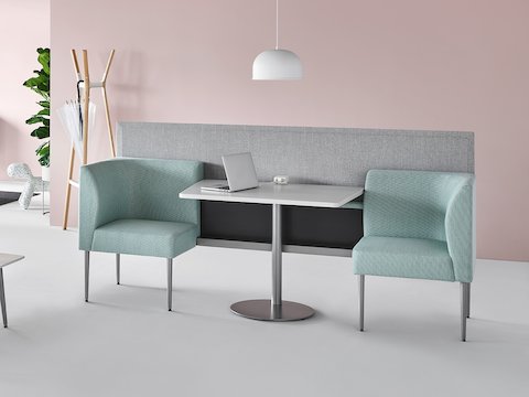 Waiting area with a focus on Nemschoff Palisade Booth, two-seat configuration, in a light green upholstery, with a center table with a white surface and a Logic power access unit, and a Nemschoff Palisade Privacy Screen attached to the back.