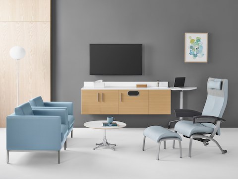 A patient room featuring Riva lounge chairs in blue textile across from a light blue Nala Patient Chair and a Nelson side table.