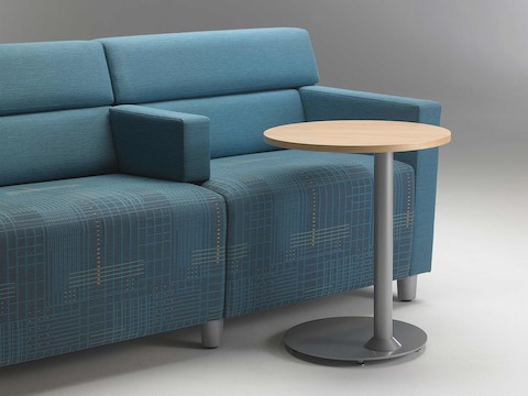 A close-up view of a Steps Lounge System in blue textile and a Steps round end table with a powder-coated base and laminate top.