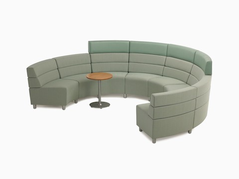A Steps Lounge System in a semi-circle in green textile and a Steps round end table with a powder-coated base and laminate top.
