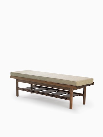 A Tamarack Table and Bench in walnut with a light-colored cushion.