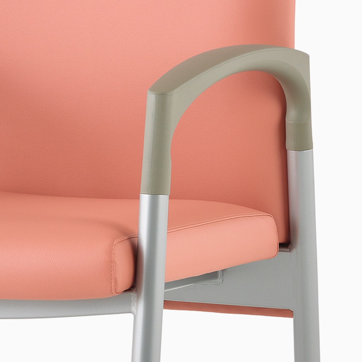 Detail of a silver frame and pewter armcap on a Valor Patient Chair upholstered in salmon pink.