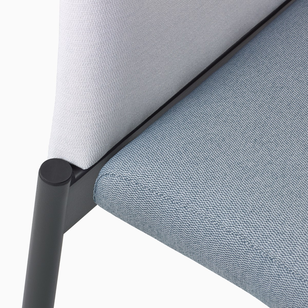 Detail of the clean-out gap in a Valor Stacking Chair without arms in a white back upholstery, a light blue seat upholstery, and a black frame.