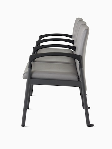 Side view of Valor three-seat multiple seating with intervening arms and legs in a medium gray upholstery, black frame, and black armcaps on white sweep.