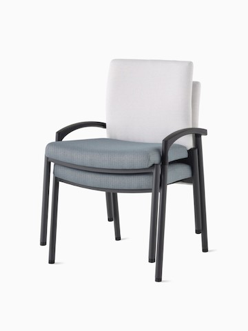 Three-quarter, front view of three Valor stacking chairs with arms stacked, with a white back upholstery and blue seat upholstery, and black frame.