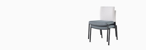 Three-quarter, front view of two Valor stacking chairs without arms stacked, with a white back upholstery and blue seat upholstery, and black frame. Three-quarter, front view of two Valor stacking chairs without arms stacked, with a white back upholstery and blue seat upholstery, and black frame.