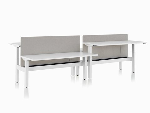 Sistema de mesas com regulagem de altura Nevi Link com superfícies de trabalho retangulares brancas e telas cinzas. Duas das quatro mesas de trabalho estão levantadas até a altura de trabalhar em pé.